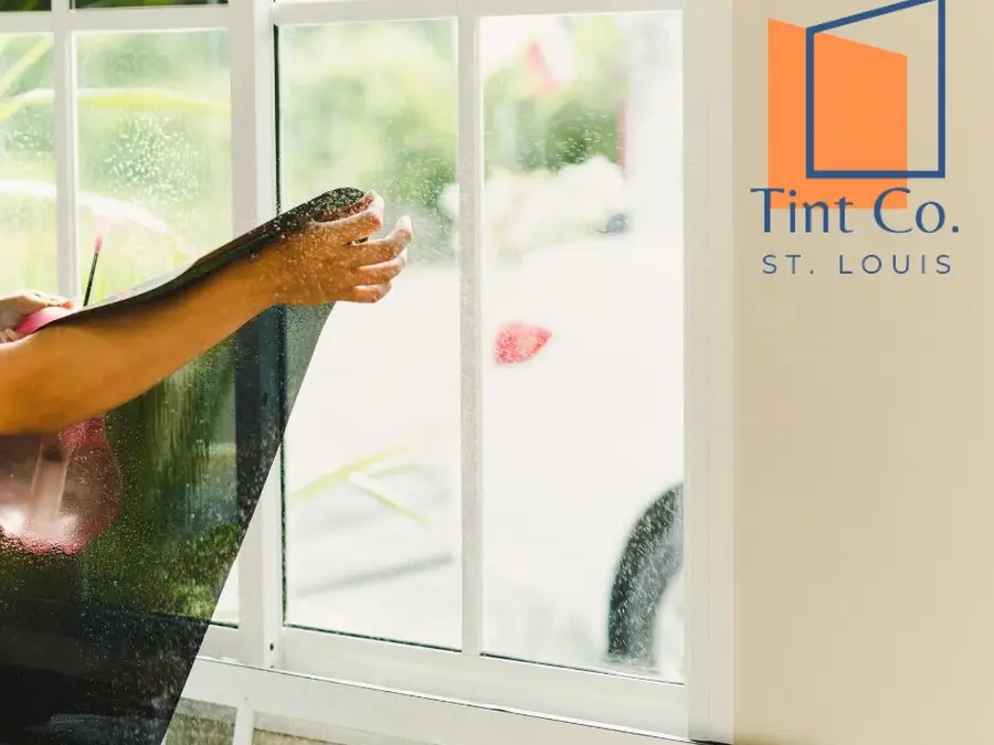 Installer peeling the liner from window film on a St. Louis window