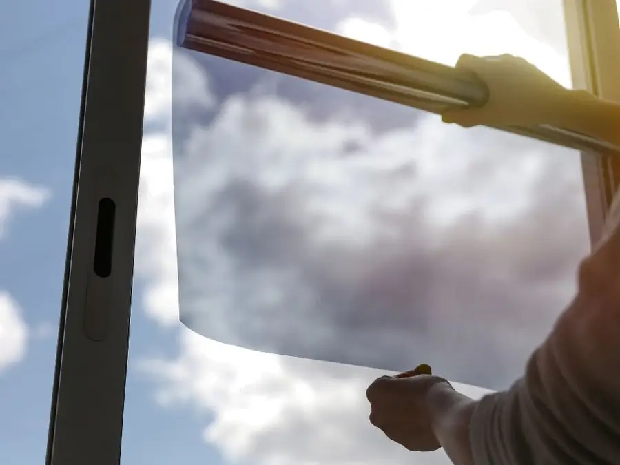 Roll of heat control window film held up against a bright sky